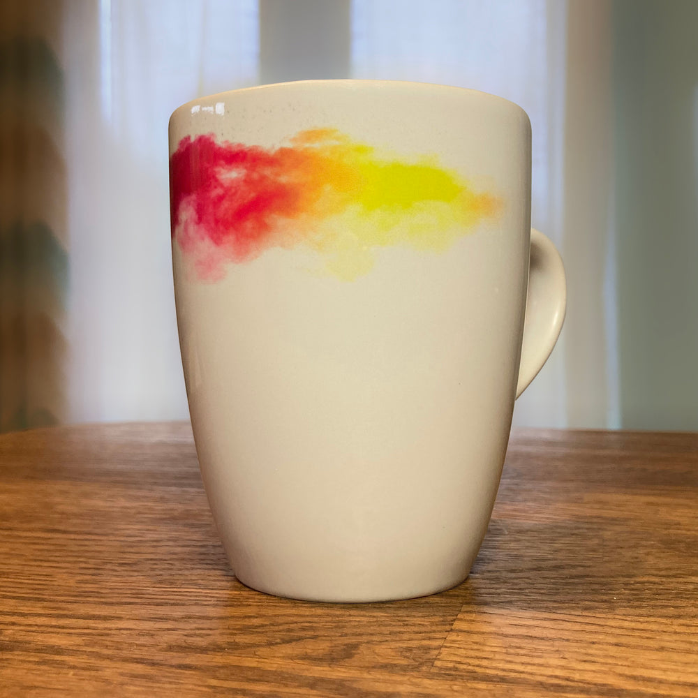 RNIB mug on a breakfast bar showing the pink to yellow part of the design